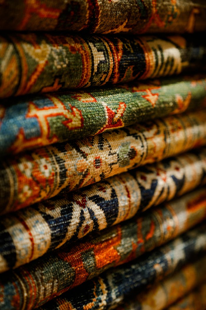Close-up view of intricately patterned oriental carpets stacked together.