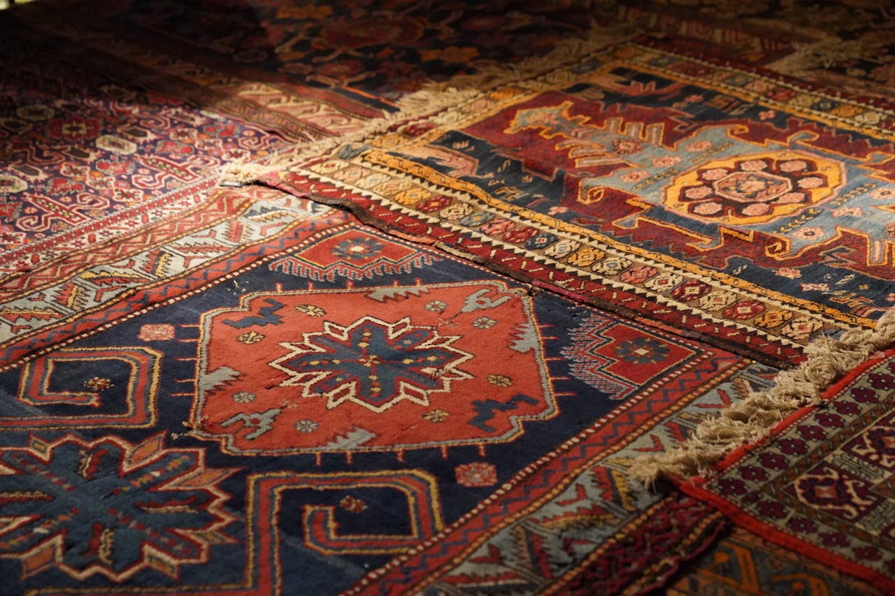 A detailed view of colorful Persian carpets with intricate geometric and floral patterns, highlighting vintage design.