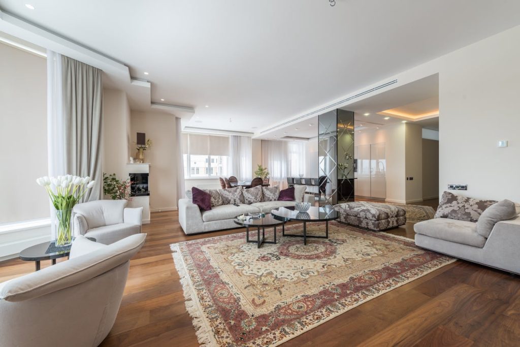 Interior of spacious living room with comfortable sofa with pillows and armchairs in luxury apartment in daylight